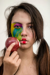 Close-up portrait of woman wearing make-up while having apple at home