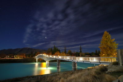 Bridge over river against sky at night