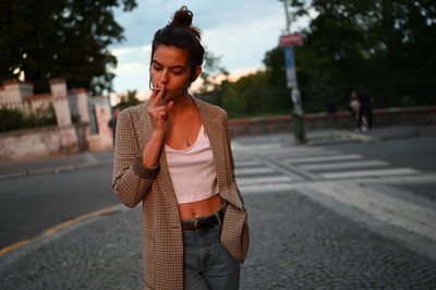 Woman smoking cigarette while standing outdoors