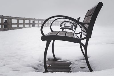 Close-up of chair on snow covered beach against sky