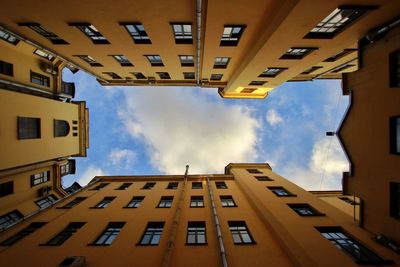 Directly below shot of buildings against cloudy sky