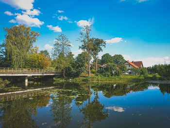 Scenic view of lake by trees and building against sky