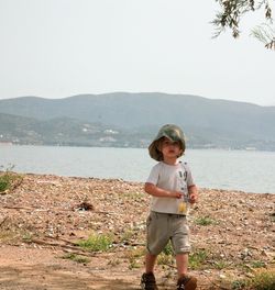 Full length of boy standing on beach against sky