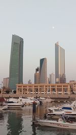 Boats in river by buildings against sky in city