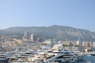 Sailboats in harbor by buildings against sky