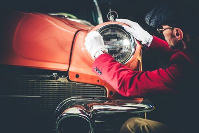 Side view of man checking vintage car headlight