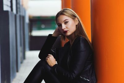 Portrait of young woman sitting against columns