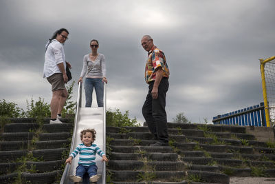 People on staircase against cloudy sky