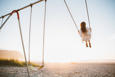 Low angle view of man swinging at beach