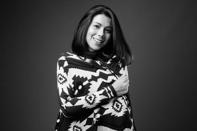 Portrait of smiling young woman against black background