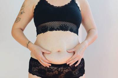 Midsection of pregnant woman standing against white background