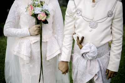 Midsection of bride and bridegroom at wedding