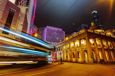 Light trails on road amidst buildings in city at night