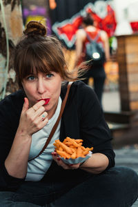 Portrait of young woman eating food in city