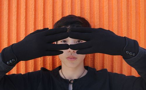 Portrait of man wearing sunglasses against orange wall