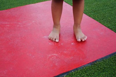 Low section of girl standing on red footpath