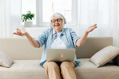 Young woman using laptop while sitting on sofa at home