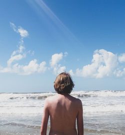 Rear view of shirtless man looking at sea against sky