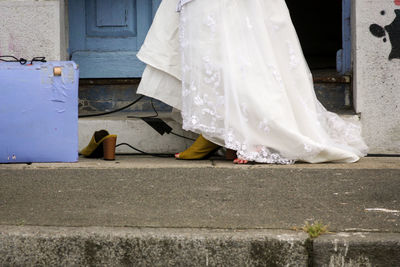 Low section of woman standing on footpath by street