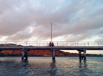 Bridge over river against sky in city
