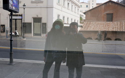 People standing on street against buildings in city