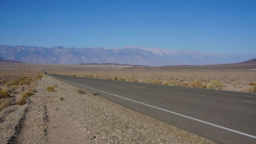 Road by desert against clear sky