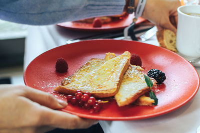 Midsection of woman having dessert in plate at table