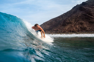 Man surfing in sea against sky