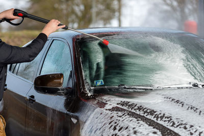 Midsection of man holding sunglasses on car