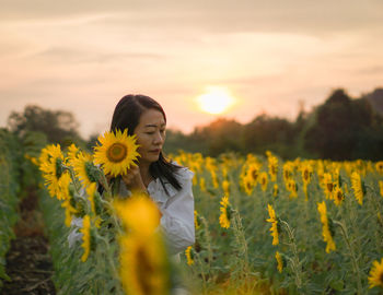 Young woman standing amidst yellow flowers
