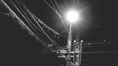 Low angle view of illuminated cables against sky at night