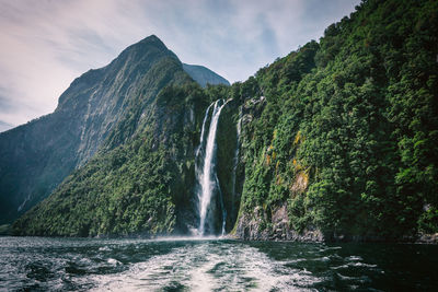 Scenic view of waterfall in forest against sky