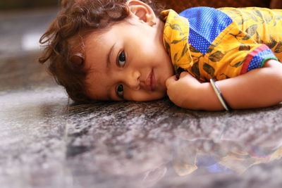 A child looking at the camera on the black marble floor