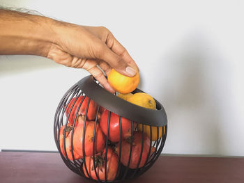 Cropped image of person holding orange on table