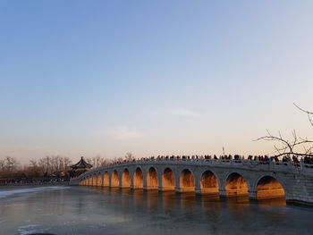 Bridge over river against sky in city