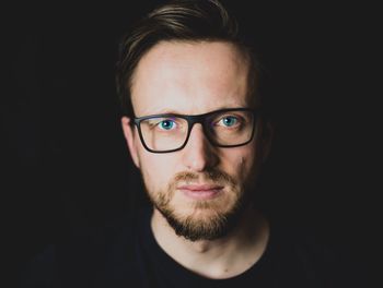 Portrait of young man against black background