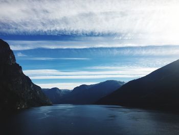 Scenic view of sea by mountains against sky