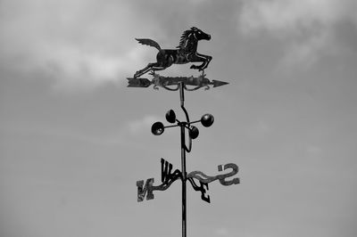 Low angle view of weather vane against sky