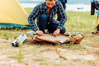 Full length of young woman sitting on tent in field