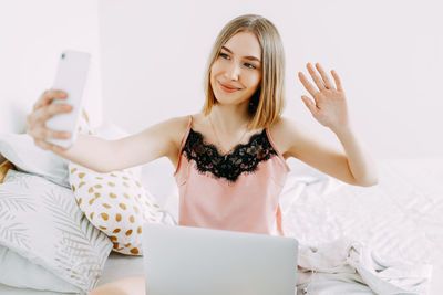 Young woman using smart phone on bed