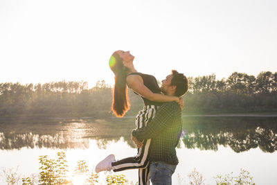 Side view of man standing by lake against sky