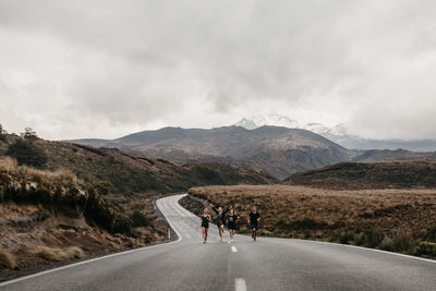 Rear view of people on road by mountain against sky