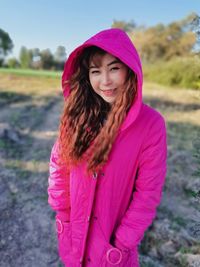 Portrait of smiling girl standing against pink background