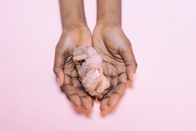 Close-up of hand holding crystal over white background