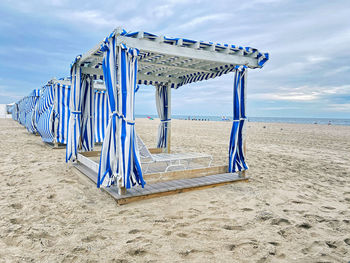 Lifeguard chair on beach against blue sky