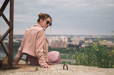 Woman wearing sunglasses sitting against sky