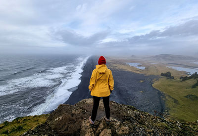 Black beach with a man in yellow jacket