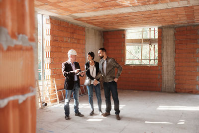 Agent explaining couple while standing in construction building