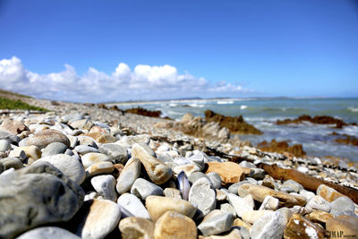 Close-up of pebbles on beach against sky