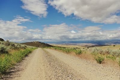 Dirt road along landscape against sky